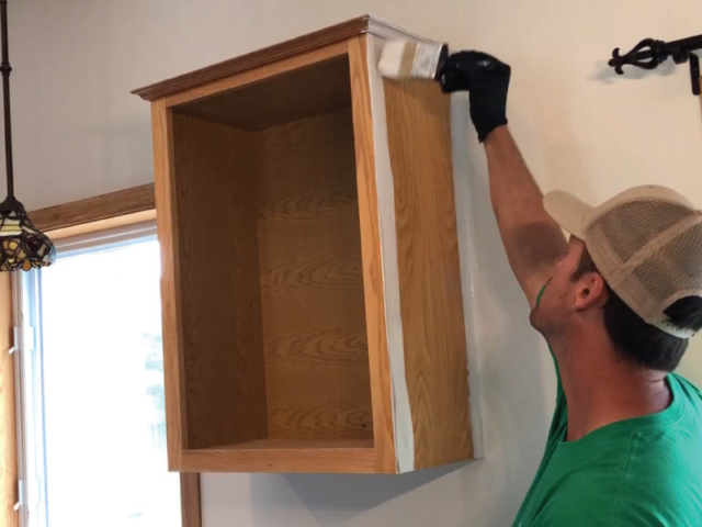 Applying coverstain oil primer with brush to kitchen cabinets